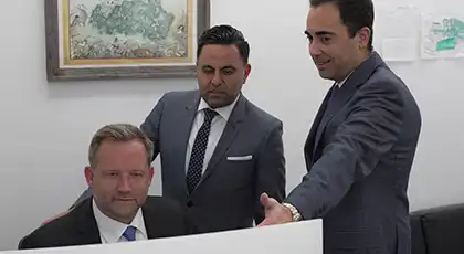 Three lawyers in suits reviewing information on a computer screen, suggesting legal consultation after an accident