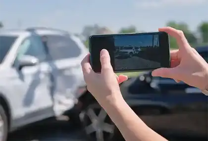  Person taking a photo of a car accident scene with a smartphone