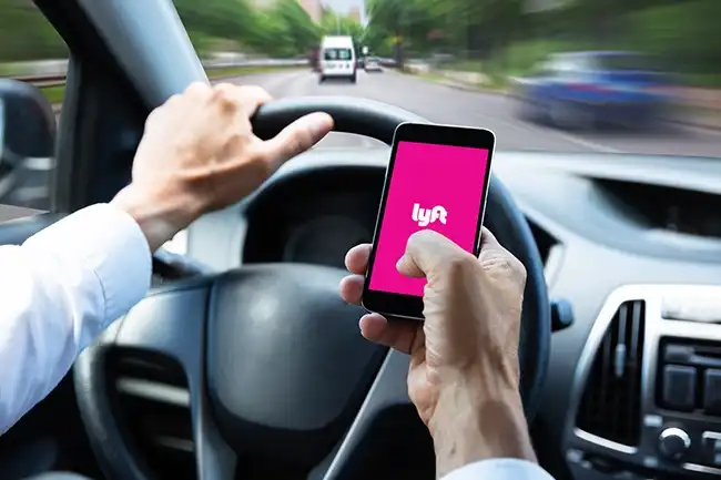 Conductor de Lyft utilizando su teléfono mientras conduce en Lakewood