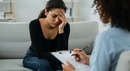 Distressed woman on couch while counselor takes notes