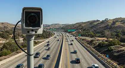 Live traffic camera overlooking a busy multi‑lane freeway through rolling hills