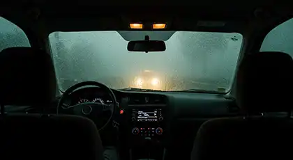 Driving at night with low visibility of the road due to heavy rains and a foggy windshield