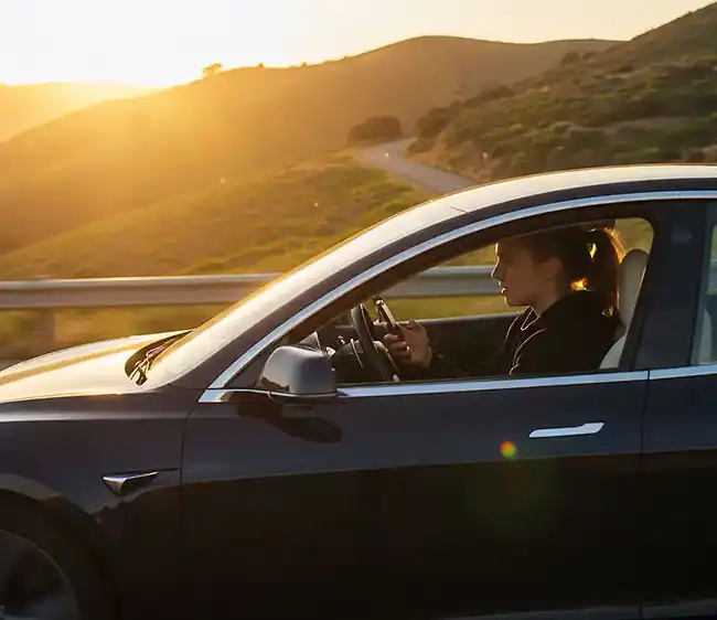 woman driving a car while using her phone