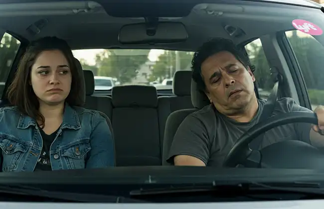 A tired Lyft driver nods off while a worried passenger looks on