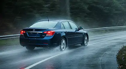 Blue car drives on wet road in heavy rain.