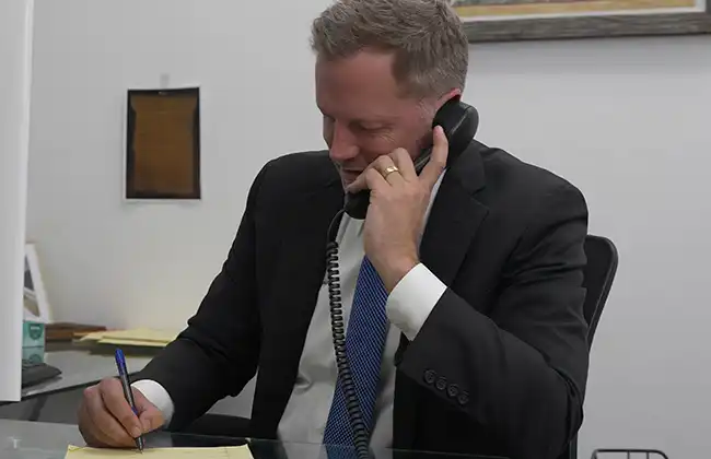 Corona car accident lawyer on the phone taking notes while assisting a client with legal questions after a crash