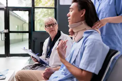 El Médico Analiza La Gravedad De Las Lesiones Y El Posible Valor De La Reclamación Con Un Paciente Que Lleva Un Collarín Tras Un Accidente