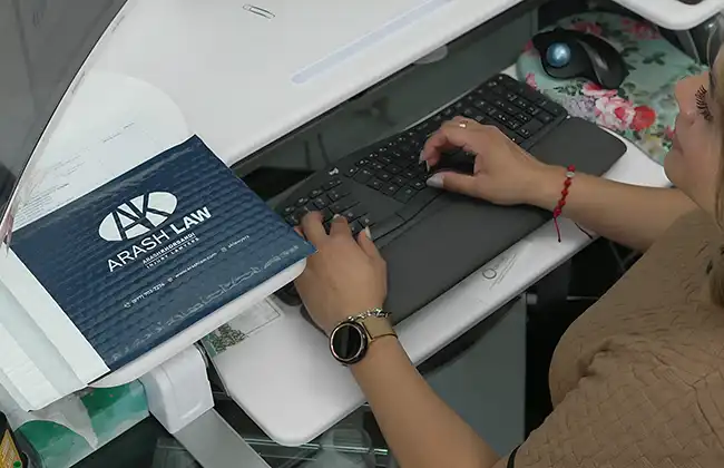 Legal assistant working at desk with Arash Law folder