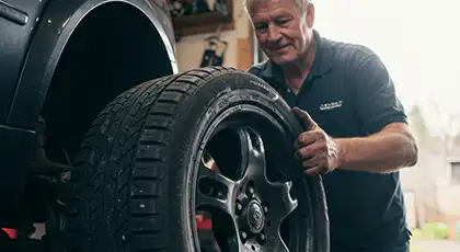 Mechanic handling a car tire in a garage