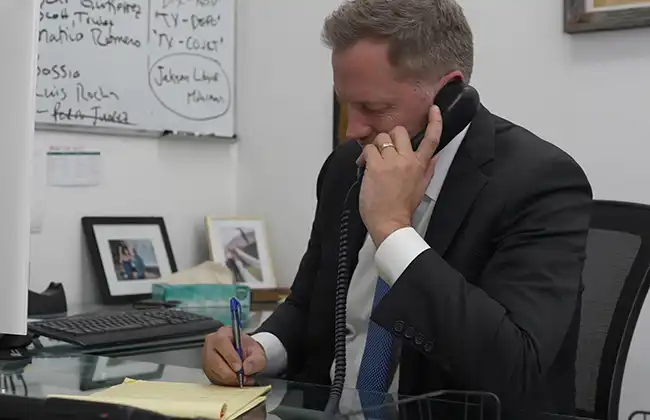 Rancho Cucamonga personal injury lawyer speaking with a client on the phone and taking notes during a consultation