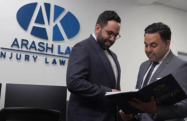 Two personal injury lawyers at Arash Law discussing a car accident case in their office