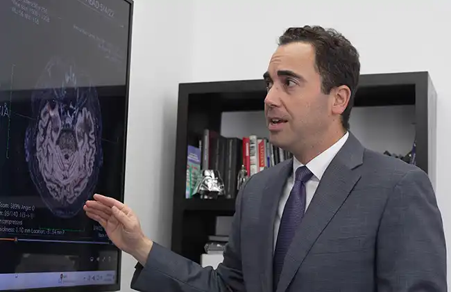 AK lawyer in a suit explains brain scan results on a screen