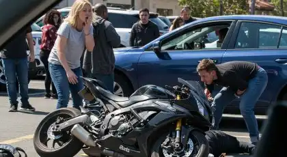 Bystanders assisting an injured motorcyclist after a crash in a parking lot