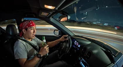 Driver holding a beer bottle while operating a moving vehicle