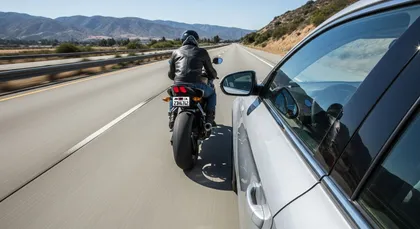 Motorcycle in a highway blind spot next to a car