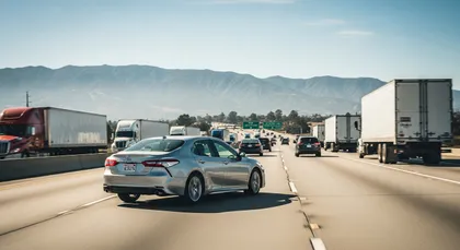 Passenger vehicle aggressively maneuvering through freeway traffic surrounded by trucks