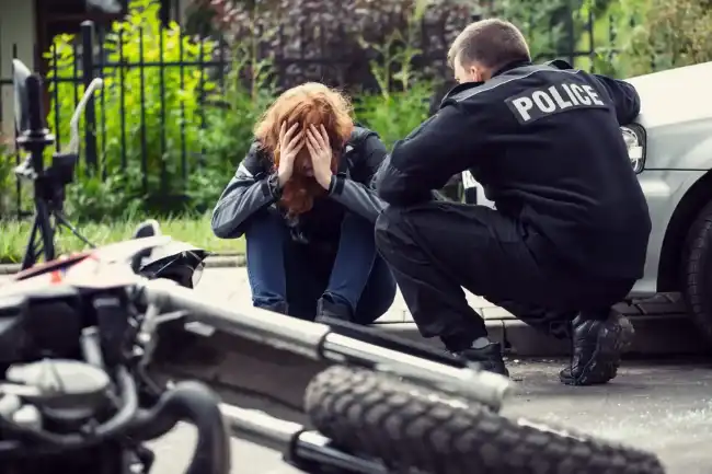 woman talking with the police on the sidewalk after a motorcycle accident