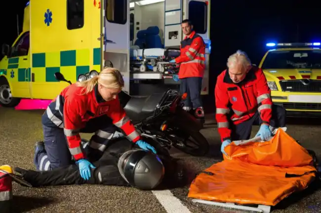 Emergency responders assisting injured motorcyclist after crash