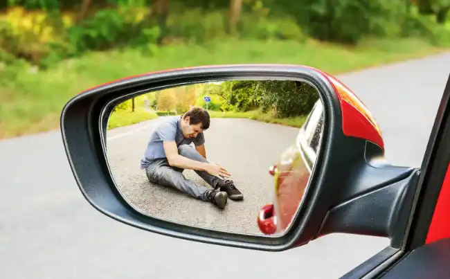 Hit-and-Run accident victim holding his feet while on the ground