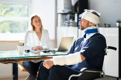 Injured man with bandages and a neck brace meeting with a lawyer after a reckless driving accident