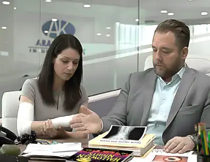 Injured woman with arm cast meeting with lawyer reviewing medical documents