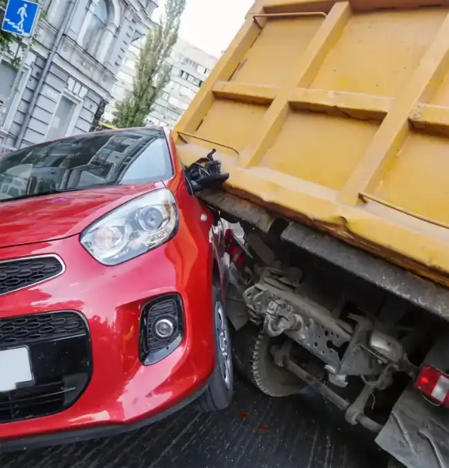 Severe collision between a red car and a dump truck highlighting the dangers of dump truck accidents