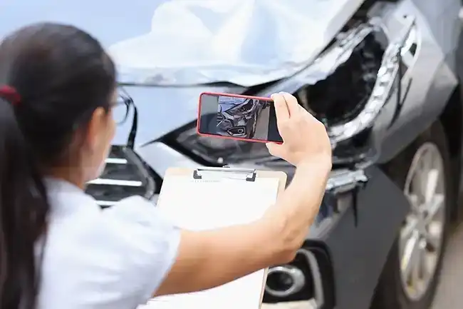 A woman taking photos of the damage to her car for an insurance claim in Napa County