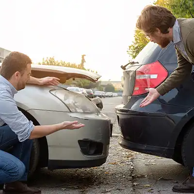 Conductores revisando daños en un choque trasero para reclamar compensación