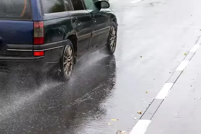 Lyft car driving on a rainy road, showing risk of accidents due to adverse weather
