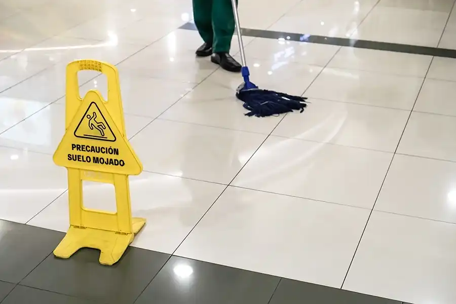 Piso mojado con señal de advertencia indicando riesgo de resbalón y caída en Costco