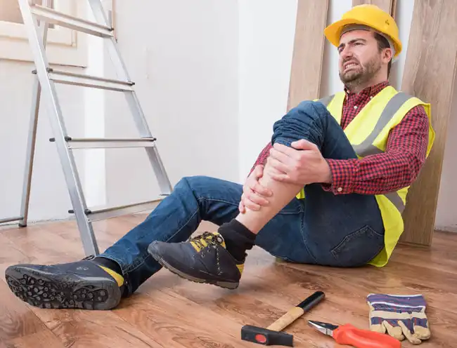Slip and fall accident victim on the ground holding his injured leg