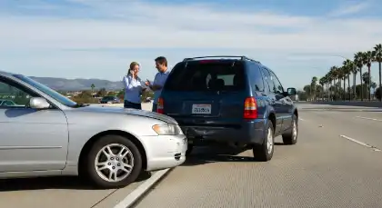 Two drivers inspecting vehicle damage after a rear-end collision on a California highway