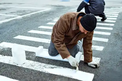 Two people painting a crosswalk at a high-risk intersection