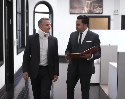 Whiplash victim consulting attorney in office hallway about filing a personal injury claim