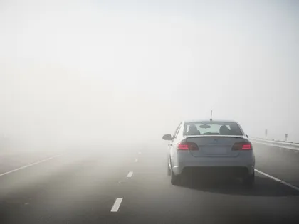 Car driving on a foggy highway with low visibility