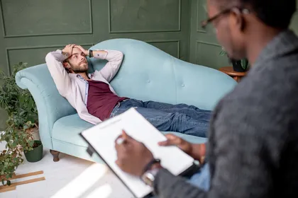 Man in therapy discussing anxiety after a car accident while lying on couch during counseling session
