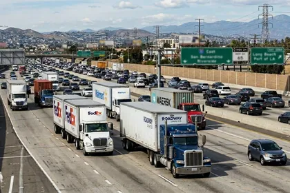 Camiones pesados y turismos que circulan por una autopista californiana de varios carriles con mucho tráfico