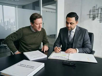 Legal consultation showing attorney and client examining binders and highlighted medical documents