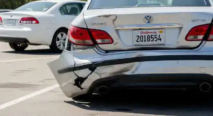 Parachoques trasero dañado de un coche tras un accidente al dar marcha atrás en un aparcamiento