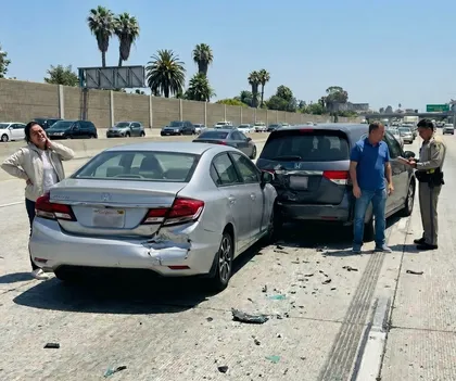 Rear-end car accident on highway with visible vehicle damage and debris on road