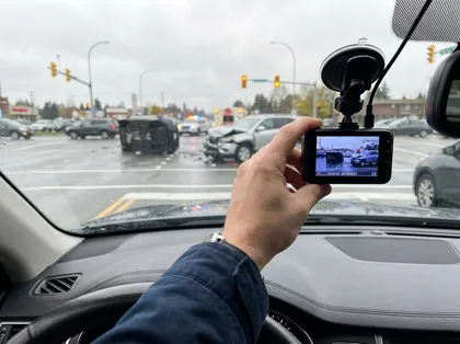 Un hombre sostiene una dashcam con imágenes grabadas como prueba para reclamar por un accidente en una intersección