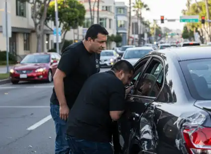 Varios transeúntes se acercan a ver cómo se encuentra el conductor herido tras un accidente de tráfico