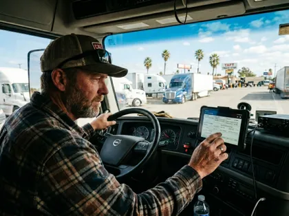 Commercial truck driver reviewing delivery information on a mounted tablet inside vehicle cab