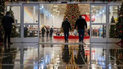 Compras en un día lluvioso- gente con adornos navideños entrando en una tienda con temática navideña y muy bien iluminada