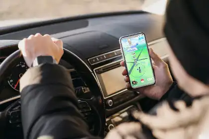 Conductor que sujeta un teléfono con un juego abierto mientras conduce