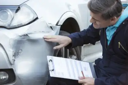 Hombre inspeccionando daño en un auto tras un accidente