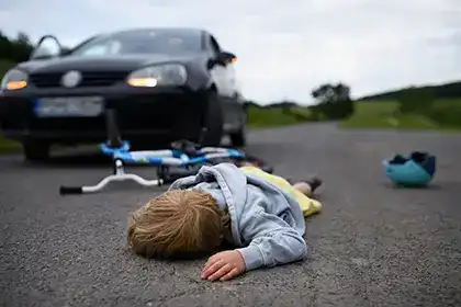 Niño en el suelo tras un accidente de bicicleta frente a un automóvil en la carretera