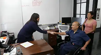 Un abogado de AK se da la mano con un hombre en silla de ruedas durante una reunión en la oficina