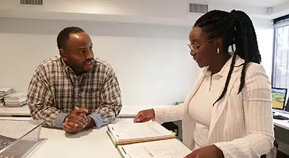 Un hombre habla con una mujer profesional que revisa un documento