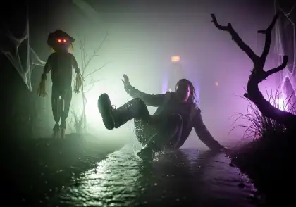 Una persona resbalándose en el suelo mojado de una casa encantada, con niebla y una iluminación inquietante